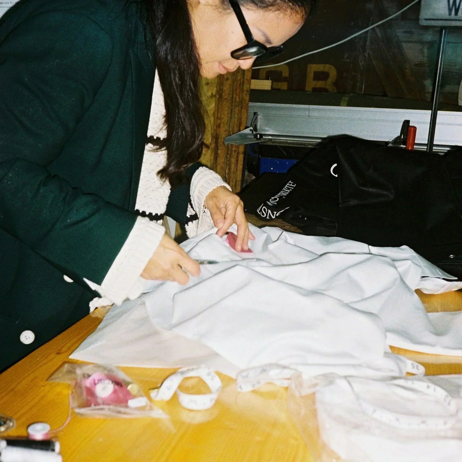 Designer Youn bei der Arbeit. Nähen von exklusiven Modepieces bei D'CONSTRUCTED, vereint Handwerkskunst und moderne Designtechniken.