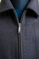 Close-up of a dark charcoal gray zip-up fleece jacket with a silver metal zipper pull, displayed on a mannequin torso over a blue shirt.